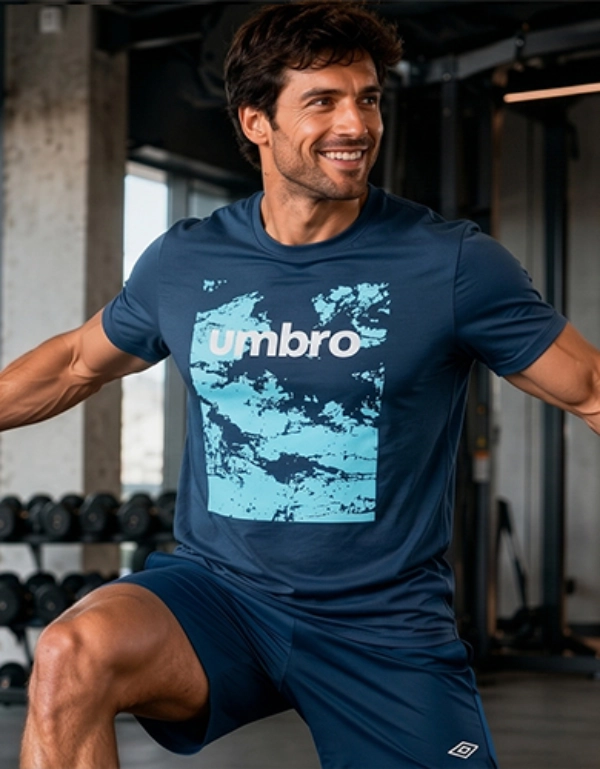 Ein Mann in blauer Sportkleidung führt eine Kabelzug‑Chest‑Fly‑Übung in einem modernen Fitnessstudio mit großen Fenstern und Trainingsgeräten aus.