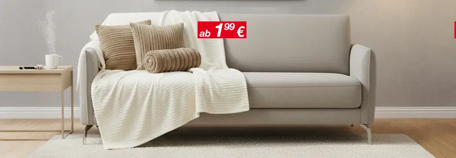 Helles Wohnzimmer mit grauem Sofa, Kissen und Decke, Beistelltisch und Stehlampe.