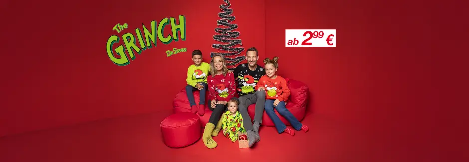 Eine Familie in bunten Weihnachtspullovern posiert auf roten Sitzsäcken vor einem festlich geschmückten Baum vor einem passenden roten Hintergrund.