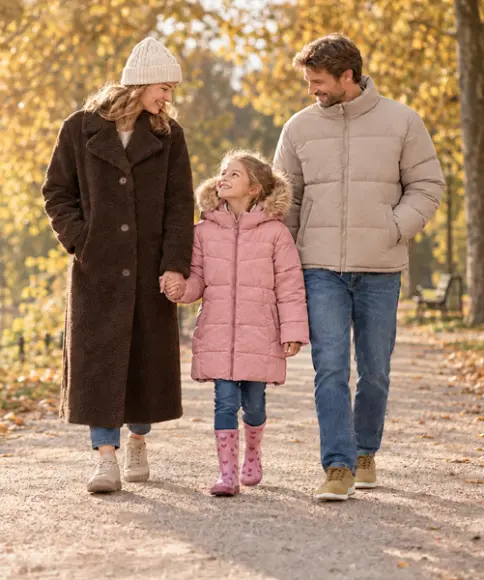 Familie in warmen Jacken bei einem herbstlichen Spaziergang am See