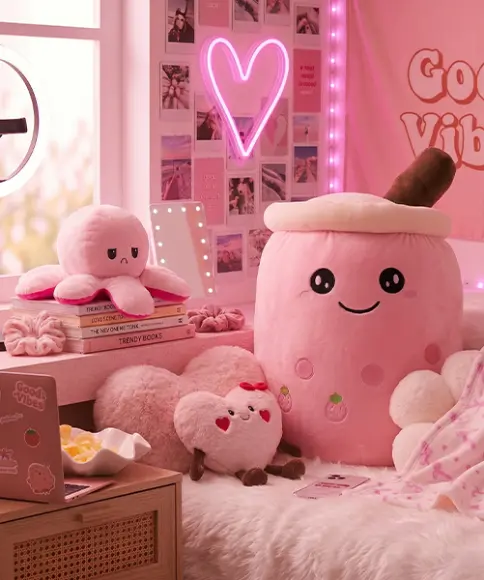 Gemütlich eingerichtetes Zimmer mit rosa Plüschtieren, Herzleuchte, Laptop und Dekoration im Social-Media-Stil – trendige Wohnaccessoires und Kuschelartikel
